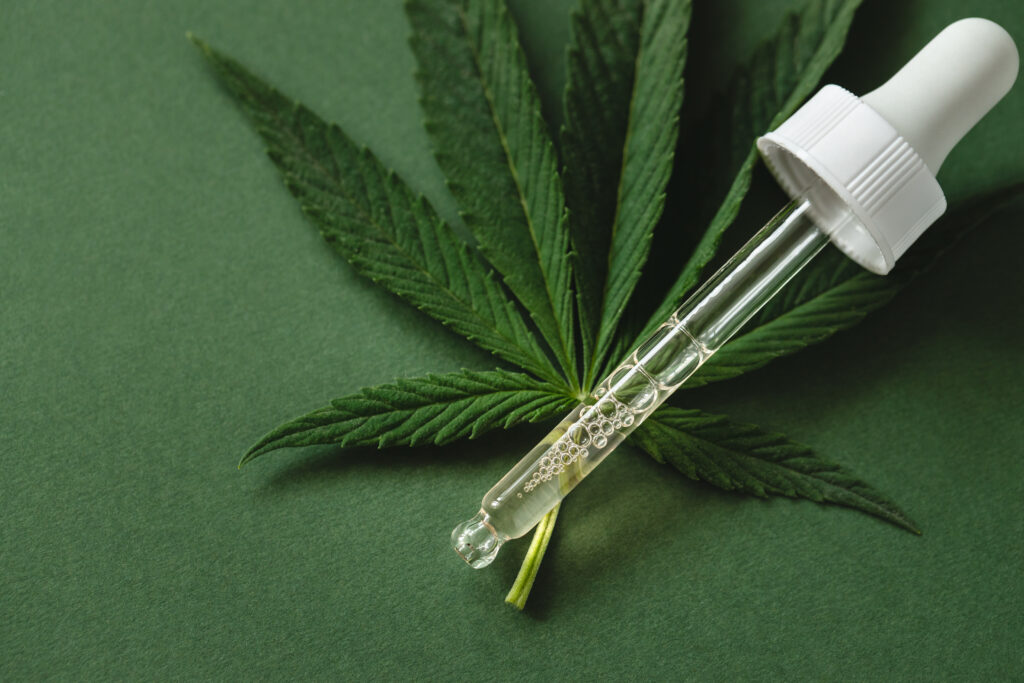 Pipette with cannabis extract on green background.